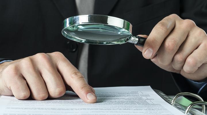 A person looking over records with magnifying glass