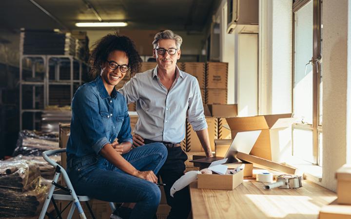 A photo of a man and a woman standing in their small business, smiling at the camera