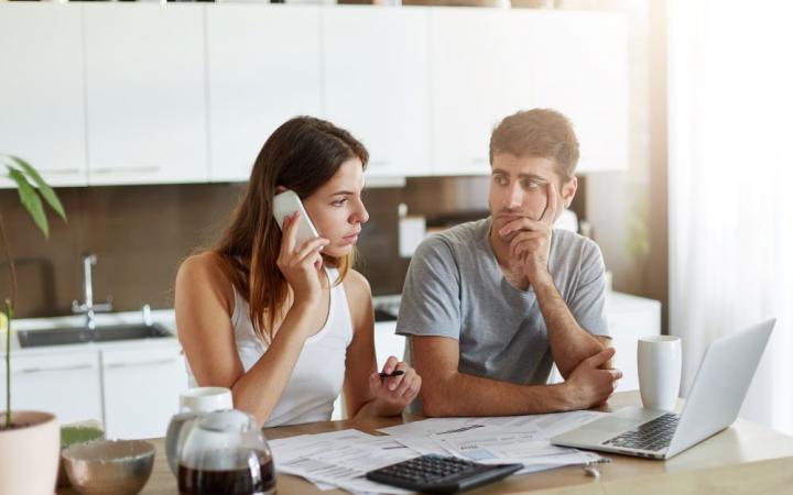 Couple on phone while looking at bills