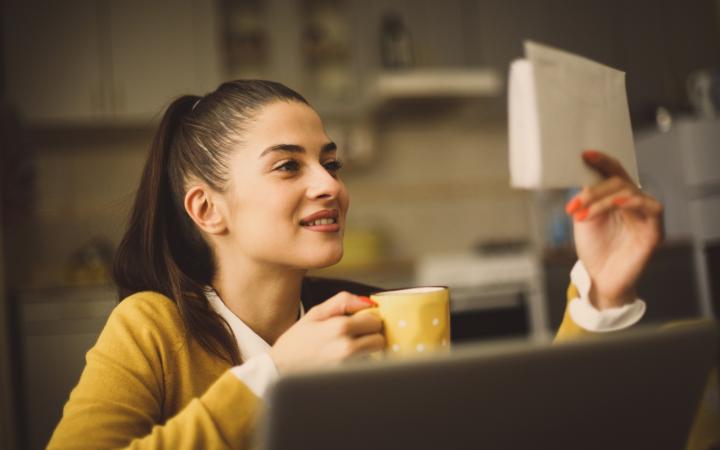 A woman looking at a bill and smiling