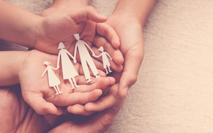 A photo of hands holding a paper cutout of a family
