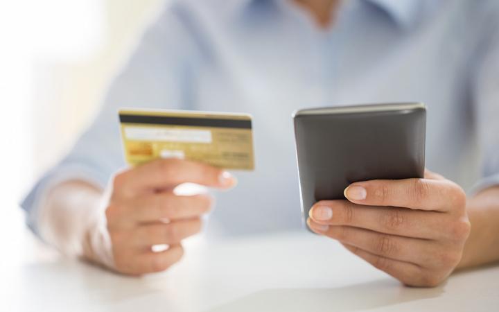 Person looking at their phone and holding a credit card