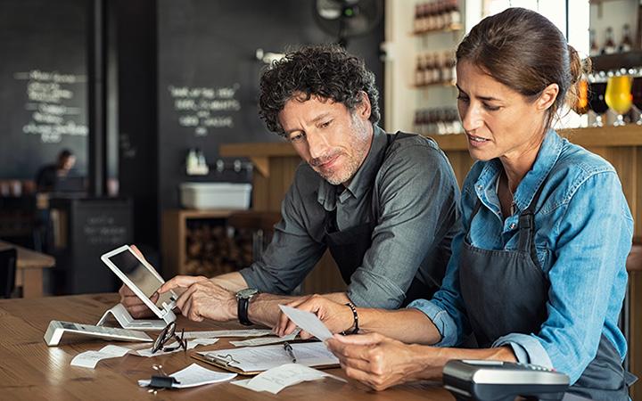 Two small business owners in a cafe looking at their bills