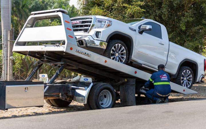 A white UTE being secured to a towing vehicle